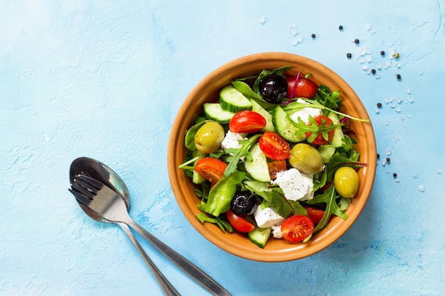 Ensalada griega con verduras frescas, queso feta y aceitunas negras sobre una piedra azul o una mesa de hormigón