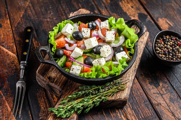 Ensalada griega con verduras frescas y queso feta en una sartén. Oscuro