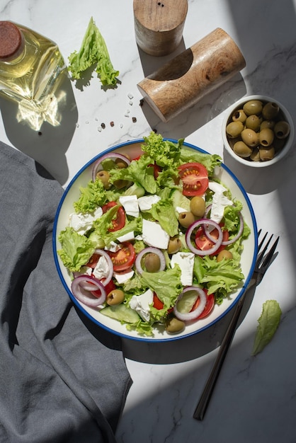 Ensalada griega con verduras y queso sobre una mesa gris