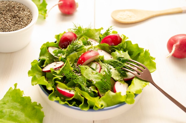 Ensalada de hierbas de lechuga de rábanos y semillas de chía y sésamo condimentadas con aceite vegetal