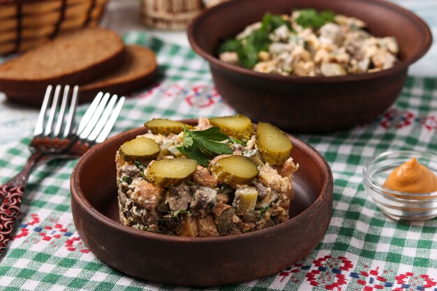 Ensalada con hígado de pollo, tortilla y pepinos encurtidos en plato marrón, formato horizontal