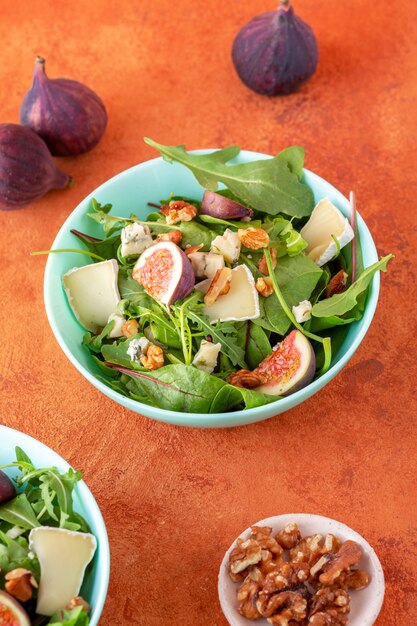 Ensalada de higos frescos con rúcula, queso y nueces sobre fondo naranja