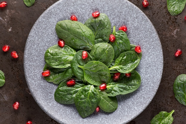 Ensalada de hojas de espinaca verde vegetariana con semillas de granada