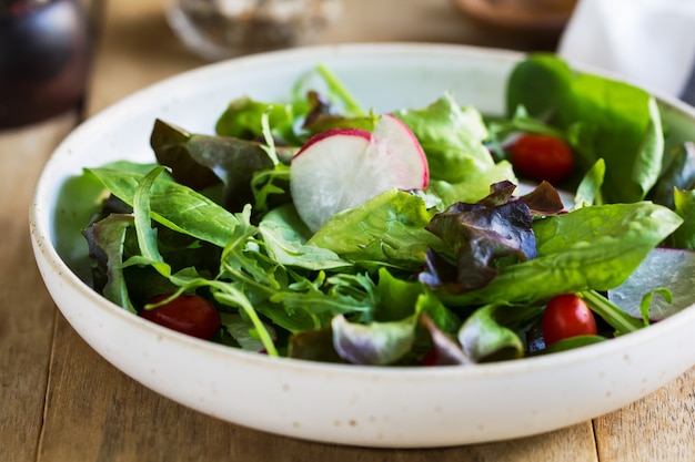 Ensalada de hojas frescas por tazón grande de ensalada y sal marina