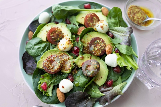 Ensalada de hojas verdes con bolas de mozzarella de granada y aguacate, tomates cherry y almendras