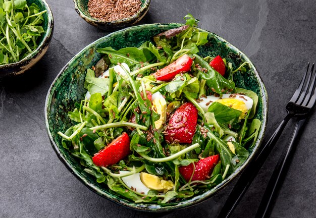 Ensalada de hojas verdes y srawberry con semillas de lino en un tazón verde