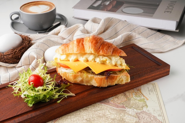 Ensalada de huevo triturado Croissants de queso con café con leche aislado en una tabla de cortar de madera vista lateral del desayuno