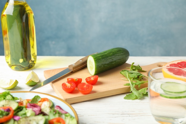 Ensalada de ingredientes, cuchillo y aceite en madera