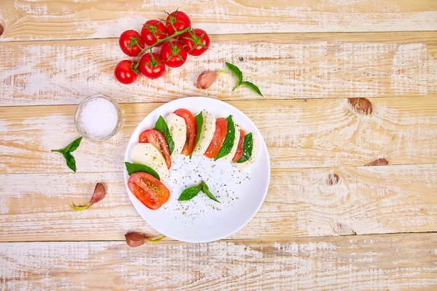 Ensalada italiana caprese con rodajas de tomate, queso mozzarella, albahaca, aceite de oliva.