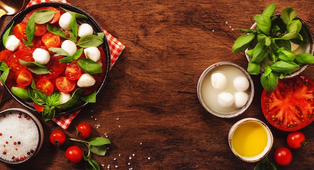 Ensalada italiana Caprese con tomates rojos y queso mozzarella con hojas de albahaca verde Vista superior mesa de madera