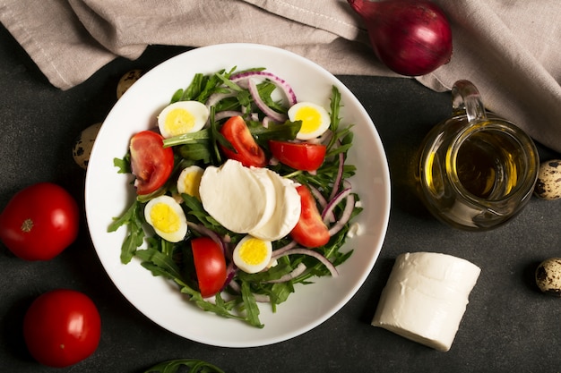 Ensalada italiana preparada con rúcula, mozzarella, huevos. Fondo negro