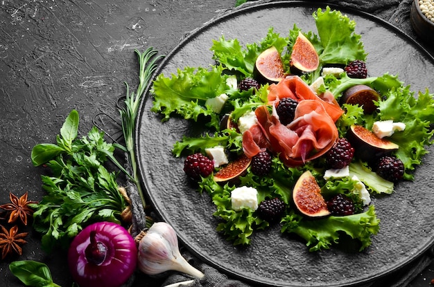 Ensalada con jamón, moras, higos y queso feta En un plato de piedra negra Comida saludable Vista superior