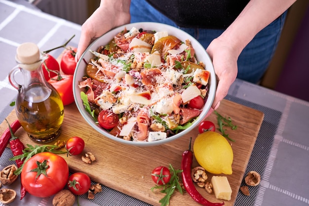 Ensalada con jamón o prosciutto peras tomates y rúcula sobre tabla de madera