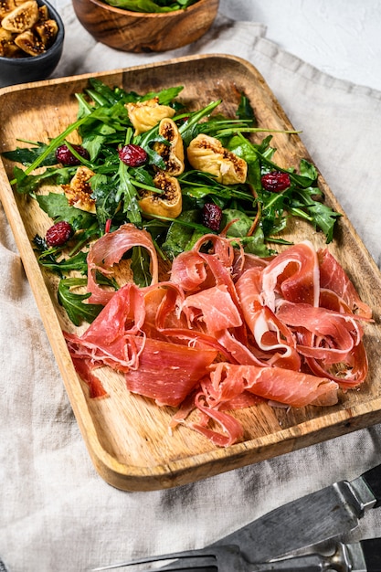 Ensalada con jamón serrano, jamón, rúcula e higo. Antipasto Fondo gris, vista desde arriba.