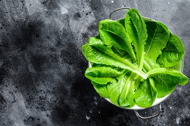 Ensalada de lechuga romana en un colador. Fondo negro. Vista superior. Copia espacio