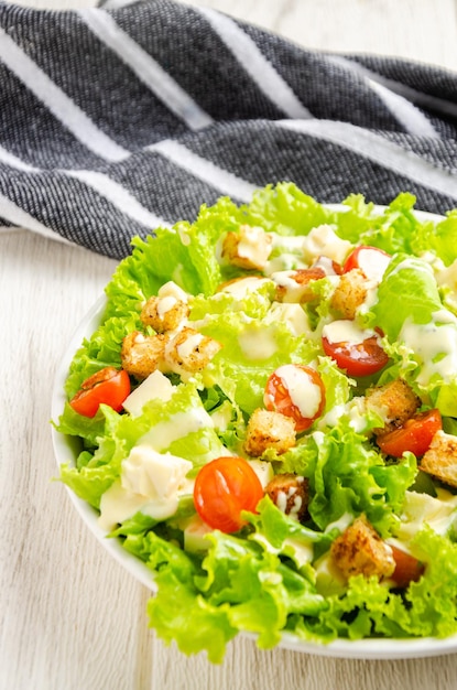 Ensalada de lechuga, tomate y queso, picatostes, aderezo, Fondo blanco.