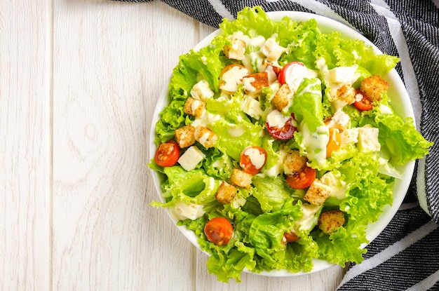 Ensalada de lechuga, tomate y queso, picatostes, aderezo, Fondo blanco.