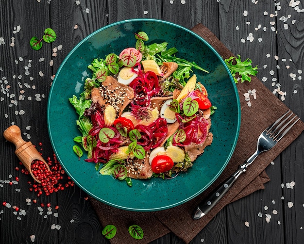 Ensalada de lengua de ternera con verduras frescas cebollas encurtidas y mini maíz en un plato