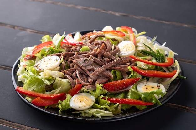 Ensalada de lengua de ternera con verduras frescas en un plato.