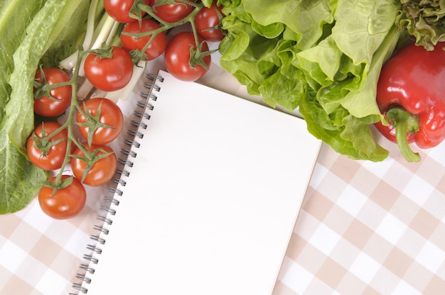 Ensalada con libro de recetas en blanco