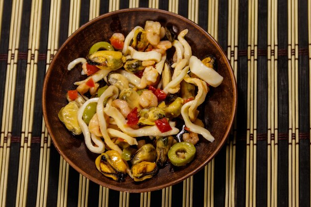 Ensalada de mariscos con camarones, calamares y mejillones en estera de bambú Vista superior