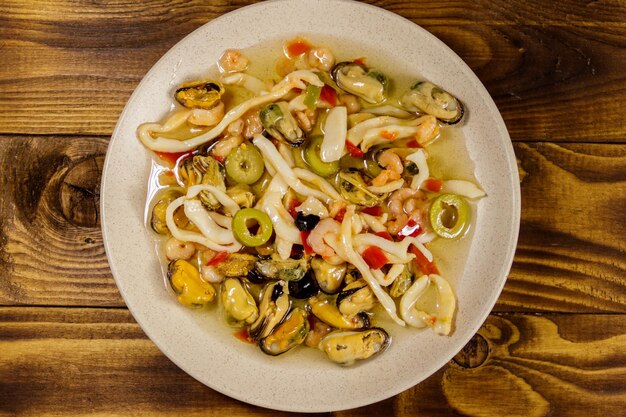 Ensalada de mariscos con camarones, calamares y mejillones en mesa de madera. Vista superior