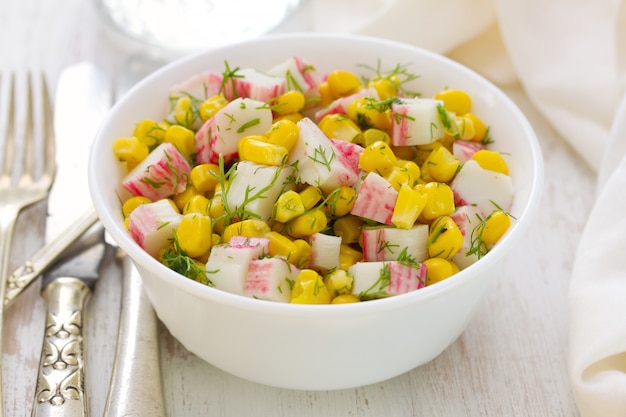 Ensalada de mariscos con maíz en un tazón blanco sobre mesa blanca