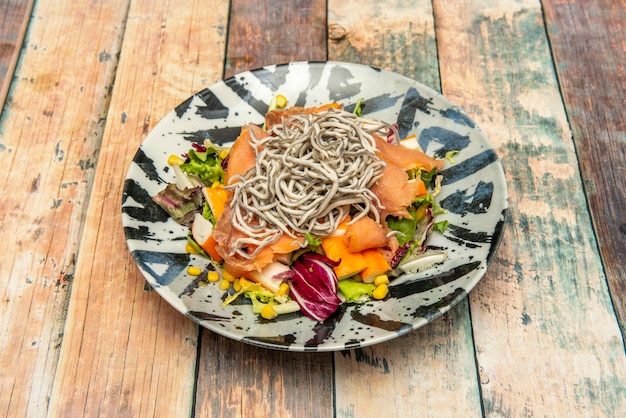 Ensalada de mariscos con salmón ahumado picado surimi gulas lechuga en brotes y maíz dulce en un plato de madera