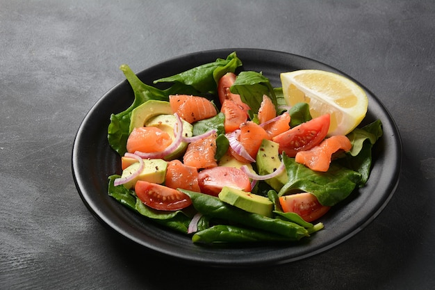 Ensalada mediterránea de aguacate y salmón con espinacas, tomates cherry, aguacate y aderezo de cebolla roja