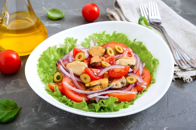 Ensalada de mejillones marinados, tomates frescos, cebollas rojas, aceitunas en un tazón blanco