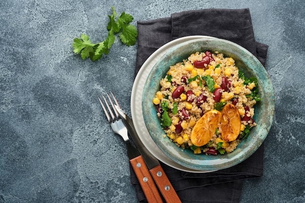 Ensalada mexicana de quinua de maíz y frijoles negros con limón caramelizado en un tazón de barro vintage antiguo sobre un fondo de hormigón gris oscuro. Plato de cocina tradicional mexicana. Vista superior, maqueta.