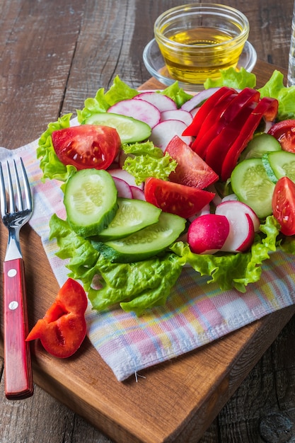 Ensalada mixta de verduras en un plato y aceite de oliva.