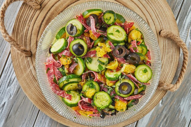 Ensalada con naranjas de calabacín y salami de cocina gourmet francesa sobre fondo de madera