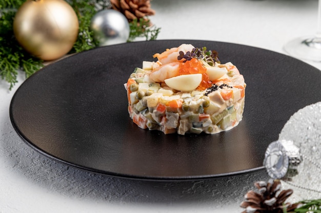 Ensalada Olivier con caviar rojo, sobre un ligero fondo navideño. plato tradicional ruso para el Año Nuevo y Navidad.