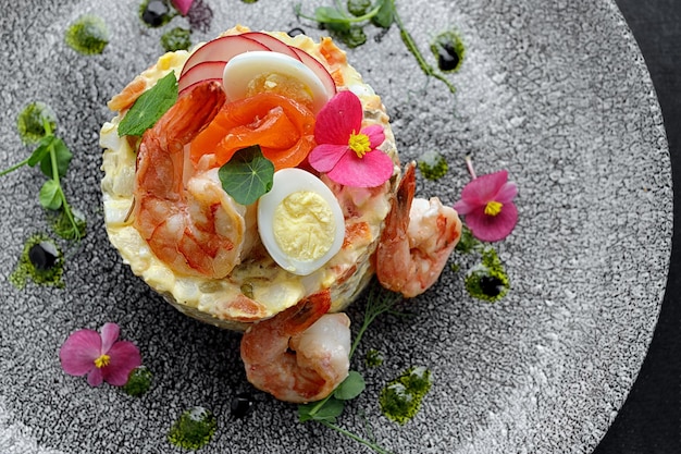 Ensalada Olivier con gambas y salmón en un plato