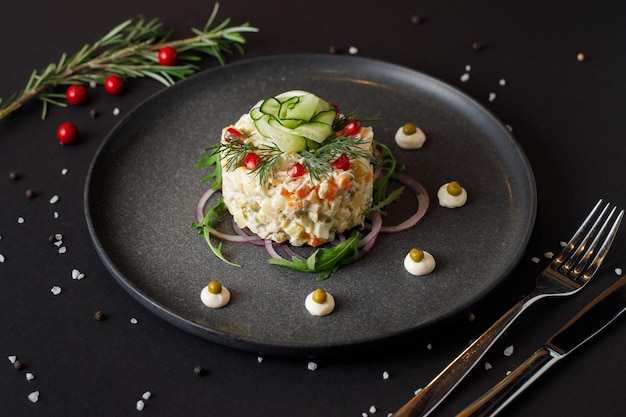 Ensalada Olivier para Navidad en una mesa negra, comida festiva europea