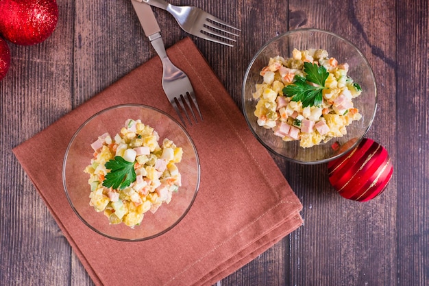 Ensalada olivier rusa de salchicha y verduras hervidas en cuencos sobre una mesa de madera Vista superior