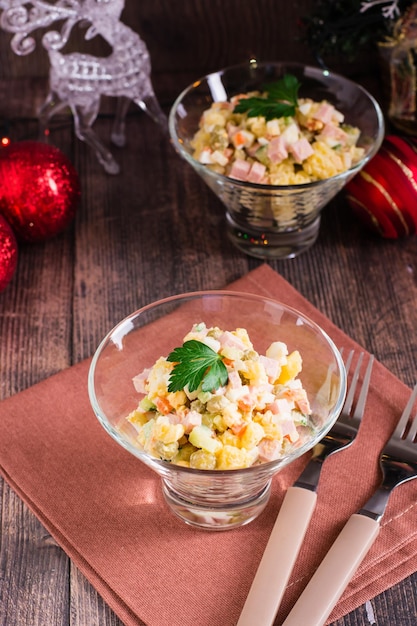 Ensalada Olivier en tazones y adornos navideños en una mesa de madera Vista vertical