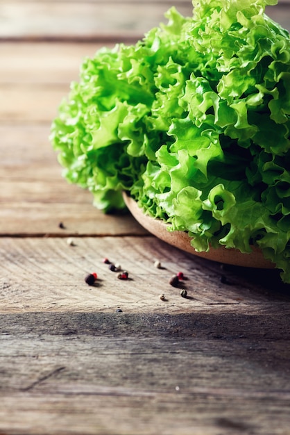 Ensalada orgánica fresca de la lechuga en de madera con pimienta. Concepto de comida sana, cruda y vegetariana.