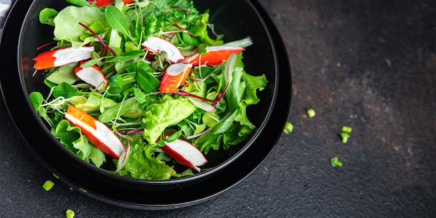 Ensalada de palitos de cangrejo hojas de lechuga verde mezclar comida fresca bocadillo en la mesa espacio de copia fondo de alimentos