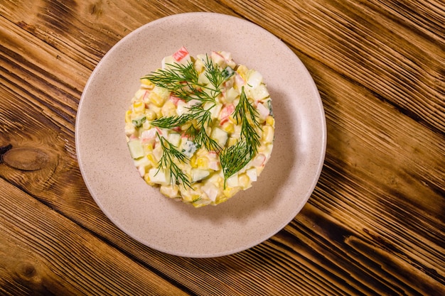 Ensalada con palitos de cangrejo, huevos cocidos y pepinos en un plato de cerámica Vista superior