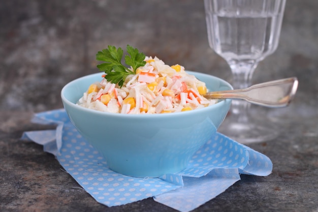 Ensalada de palitos de cangrejo de maíz y col en un plato azul