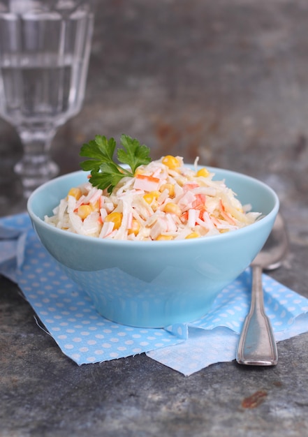 Ensalada de palitos de cangrejo de maíz y col en un plato azul