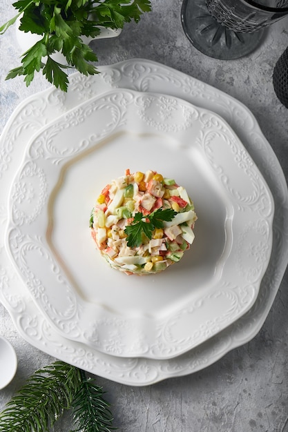 Ensalada de palitos de cangrejo servido en plato blanco sobre mesa de piedra gris