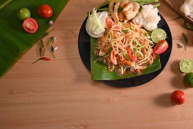 Ensalada de papaya o Som tum sobre fondo de mesa de madera Tradicional de comida tailandesa