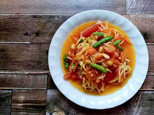 Ensalada de papaya picante comida tailandesa sobre fondo de madera