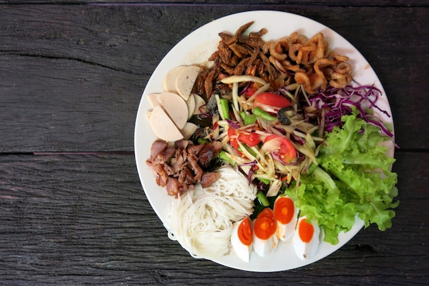 Ensalada de papaya tailandesa o Som Tum en el plato blanco de la mesa de madera