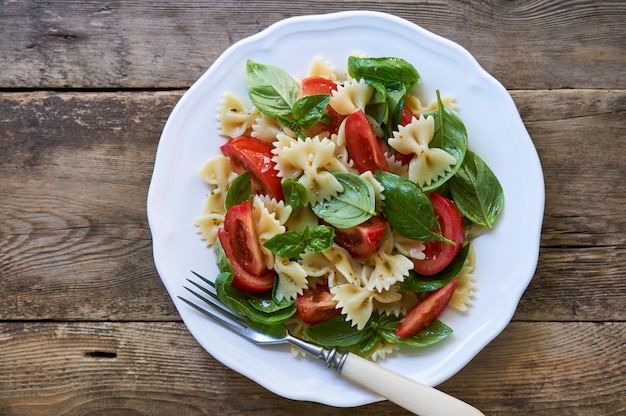 Ensalada de pasta farfalle con tomate y albahaca verde