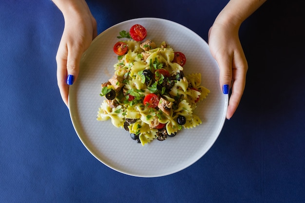 Ensalada de pasta fusili, con pesto de rúcula, jugosos tomates, aceitunas y cebolla.