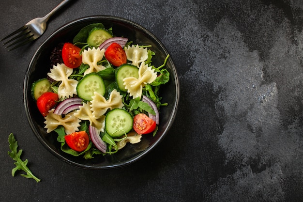 Ensalada de pasta italiana farfalle, verduras, mezclar hojas, vista superior